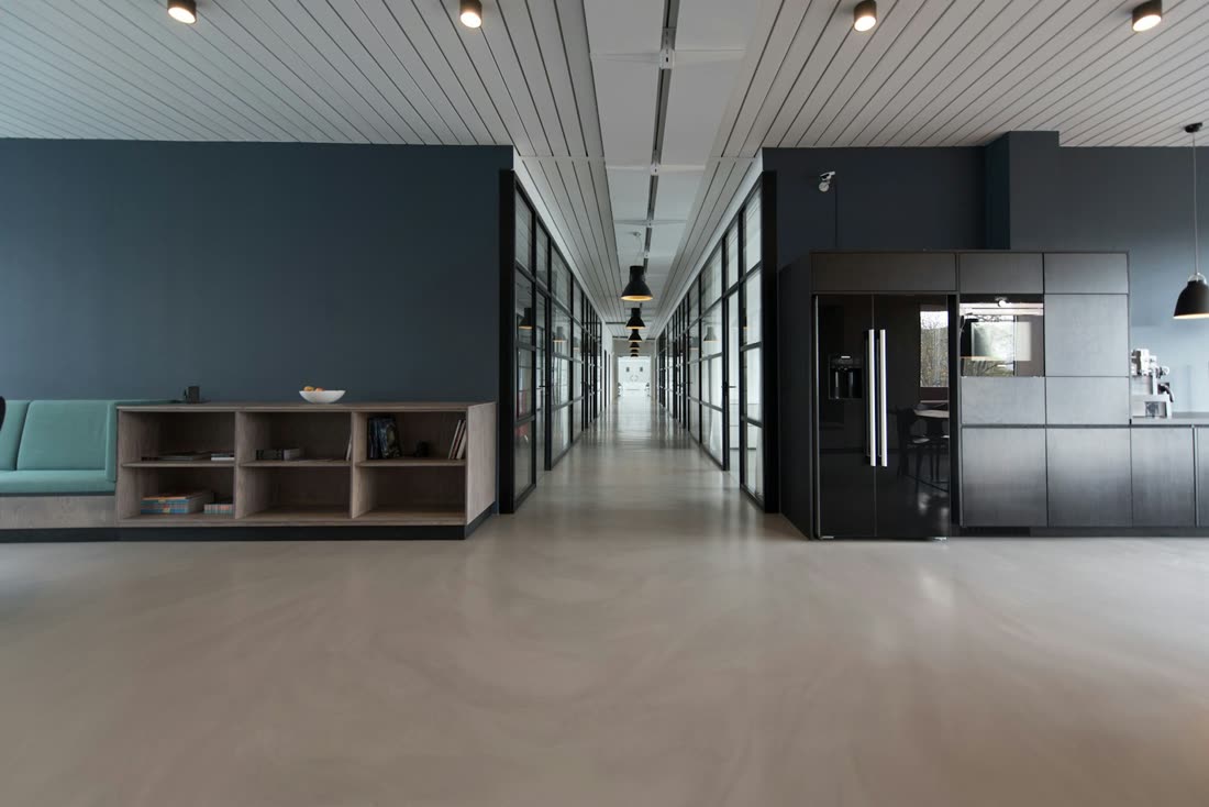 A clean, modern workplace break area with a refrigerator, coffee station, and seating