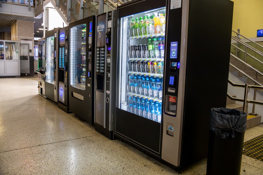 A row of vending machines installed along a commercial building corridor