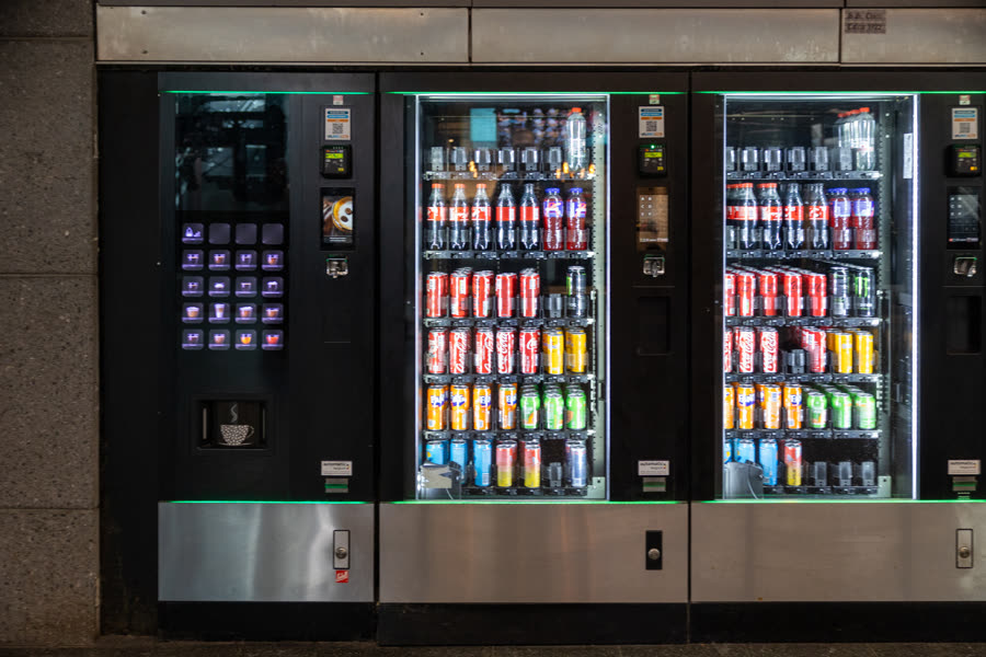 Modern snack and beverage vending machines with card readers, fully stocked and lit